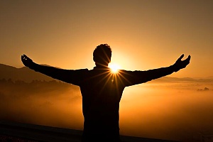 a man with outstretched arms overlooking a sunset after he quit drinking alcohol