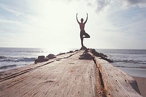 woman doing a yoga pose on the beach and being positive