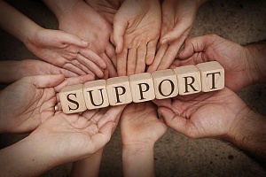 the word support spelled out using wooden blocks on a group of hands