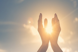 hands cupping the sun in the sky symbolizing a helping hand through recovery