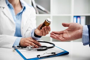 female doctor giving pills bottle to male patient in clinic during Outpatient Drug Treatment Programs