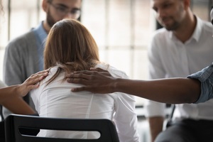 unhappy woman with supporting diverse people at therapy session