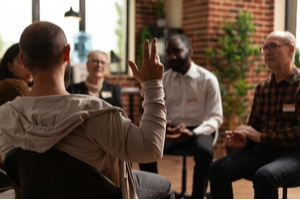 man with addiction sharing health problems with group at a meeting