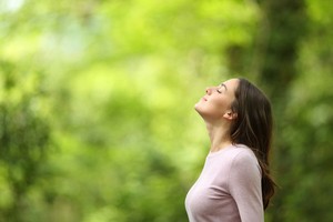 A woman breathing with joy near greenery