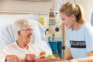 A woman is volunteering in the daycare of old age patients