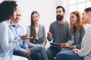 Six people are talking to one another in a group meeting session