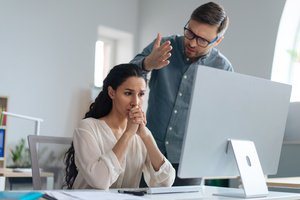 A man scolding a woman working on a computer