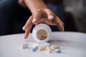 A woman trying to grab a bottle of tablets and pills