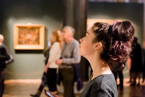 A woman in an art museum full of people