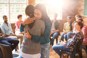 Two women hugging each other during a group support activity