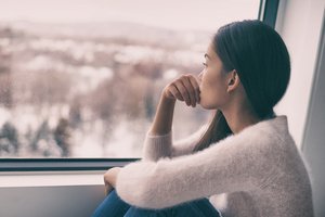 A depressed woman sitting at the window