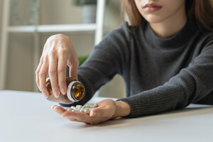 Women struggling with addiction pouring out pills into her hand