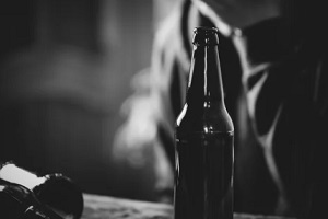 stressed man behind alcohol bottle