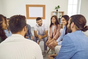 different people sitting in a circle, talking and smiling during a group therapy session in DC
