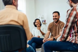 adult man, looking happy, talking with random people from the group therapy