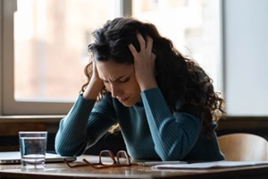 unhappy female overworked and stressed sit at desk with closed laptop suffer from headache