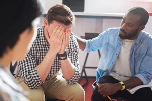 reliable kind black man putting his hand on the shoulder of a crying person while talking to him