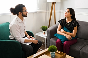 Happy young woman at therapy with female professional psychologist