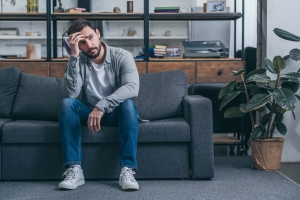 Sad Man Sitting on Couch Thinking about Having Therapy