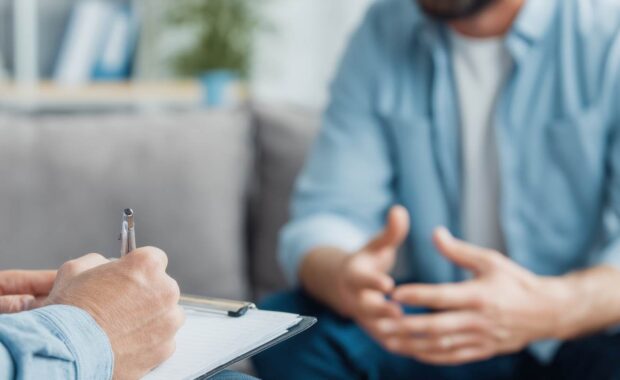 Therapist Taking Notes While Talking to A Man Struggling with Mental Health