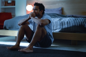 Man with Emotional Stress Sitting on Floor in Bedroom